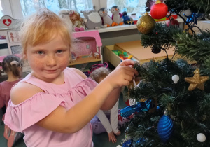 Dziewczynka zawiesza ozdoby na choince