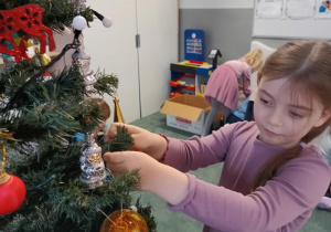 Dziewczynka zawiesza ozdoby na choince