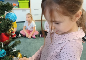 Dziewczynka zawiesza ozdoby na choince