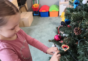 Dziewczynka zawiesza ozdoby na choince
