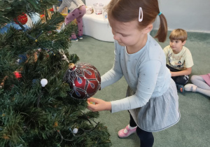 Dziewczynka zawiesza ozdoby na choince