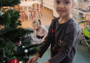 Dziewczynka zawiesza ozdoby na choince