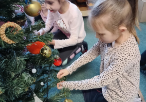 Dziewczynki zawieszają ozdoby na choince