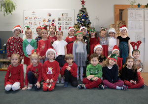 Dzieci pozują do zdjęcia na tle choinki