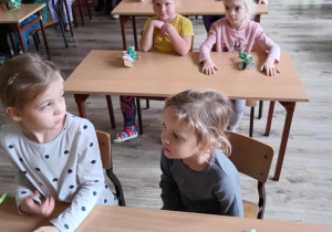 Dzieci siedzą w szkolnych ławkach