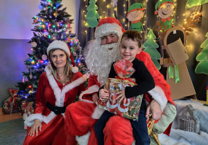 Zdjęcie chłopca pozowane z Mikołajem w świątecznej aranżacji