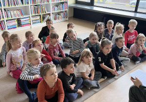 Dzieci na dywanie w bibliotece miejskiej słuchające bajki