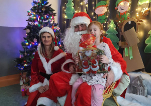 Zdjęcie dziewczynki pozowane z Mikołajem w świątecznej aranżacji