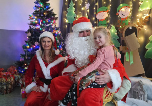 Zdjęcie dziewczynki pozowane z Mikołajem w świątecznej aranżacji