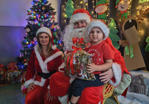 Zdjęcie chłopca pozowane z Mikołajem w świątecznej aranżacji