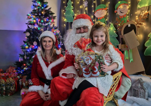 Zdjęcie dziewczynki pozowane z Mikołajem w świątecznej aranżacji