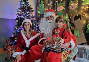 Zdjęcie dziewczynki pozowane z Mikołajem w świątecznej aranżacji