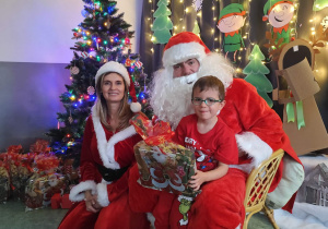 Zdjęcie chłopca pozowane z Mikołajem w świątecznej aranżacji