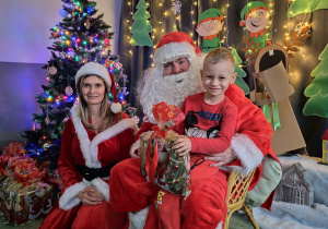 Zdjęcie chłopca pozowane z Mikołajem w świątecznej aranżacji