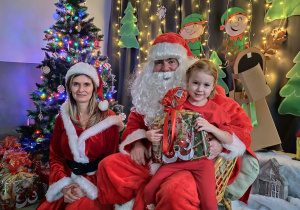 Zdjęcie dziewczynki pozowane z Mikołajem w świątecznej aranżacji