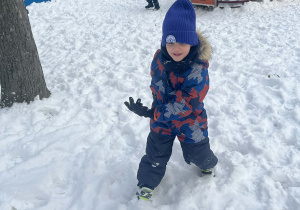 Chłopiec biegający po ogrodzie podczas zabaw zimowych