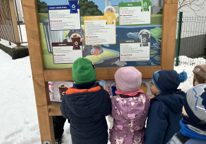 Dzieci opisujące segregację odpadów - korzystanie z tablicy edukacyjnej w ogrodzie przedszkolnym