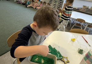 chłopiec wysypuje choinkę ryżem