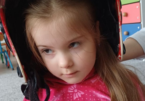 dziewczynka pozuje w kasku strażaka