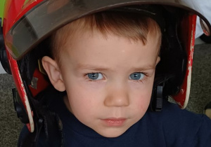 chłopiec pozuje w kasku strażaka