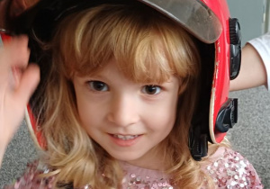 dziewczynka pozuje w kasku strażaka