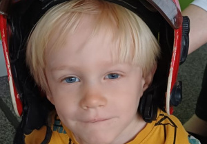 chłopiec pozuje w kasku strażaka