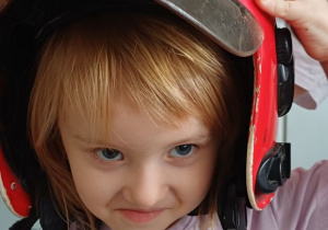 dziewczynka pozuje w kasku strażaka