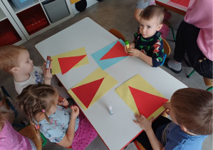 dzieci wykonują pracę plastyczną "Mikołaj"