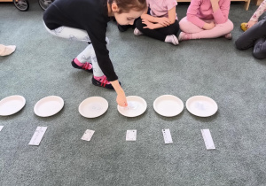 Dziewczynka odkłada literę na przypisany jej talerzyk