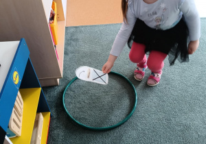 Dziewczynka zastanawia się, czy odłożyć obrazek przedstawiający pokrywkę od słoika do zielonego koła