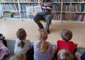 Dzieci słuchają książki czytanej przez pana bibliotekarza