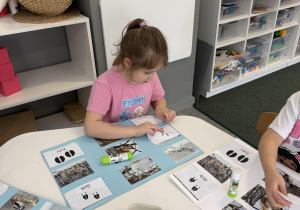 dzieci przy stołach wykonują karty pracy