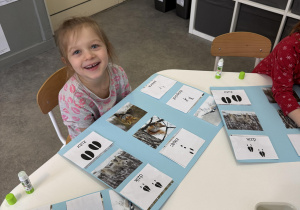 dzieci przy stołach wykonują karty pracy