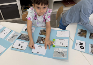 dzieci przy stołach wykonują karty pracy