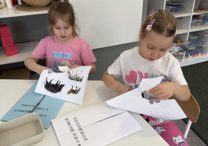 dzieci przy stołach wykonują karty pracy