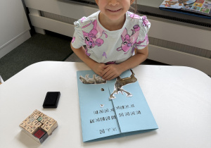 dzieci przy stołach wykonują karty pracy