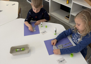 dzieci przy stołach wykonują karty pracy