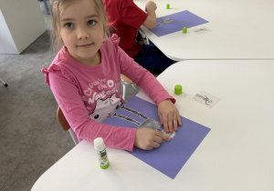 dzieci przy stołach wykonują karty pracy