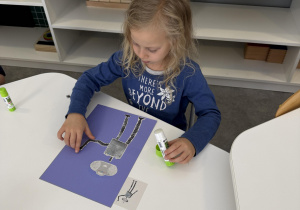 dzieci przy stołach wykonują karty pracy