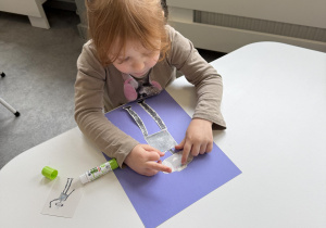 dzieci przy stołach wykonują karty pracy