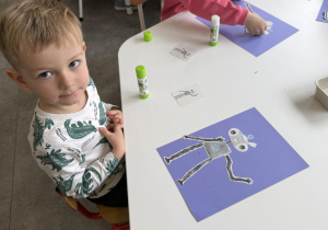 dzieci przy stołach wykonują karty pracy