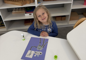 dzieci przy stołach wykonują karty pracy