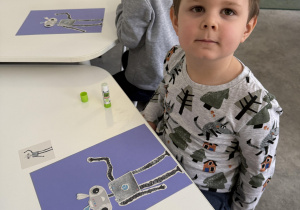 dzieci przy stołach wykonują karty pracy