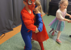 Dzieci tańczące w parach podczas balu karnawałowego na sali gimnastycznej