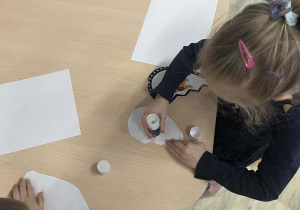 Dzieci wykonujące prace plastyczną przy stoliku