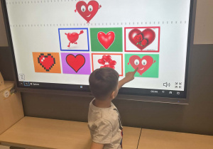 Chłopiec podczas rozwiązywania zagadek na tablicy interaktywnej