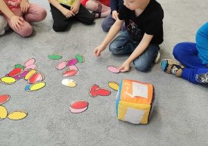 Układanie zabawy dydaktycznej z elementami przeliczania na dywanie