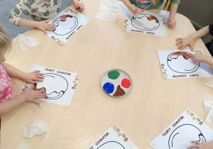 Dzieci wykonujące prace plastyczne przy stolikach - tłusty czwartek