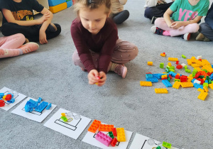 Dziewczynka podczas układania klocków na planszy na dywanie