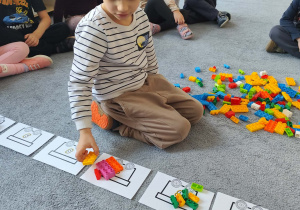 Chłopiec podczas układania klocków na planszy na dywanie